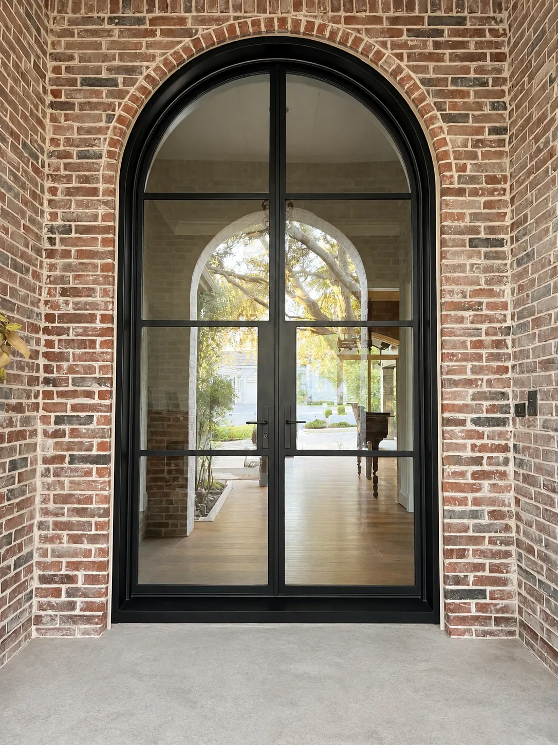 Black steel-and-glass double entry fitted to the same full brick arch