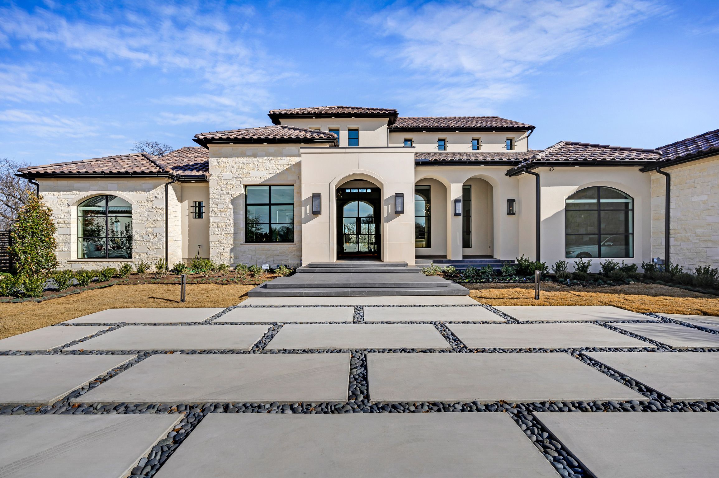 Front facade with a stucco-arched porch over a straight-top steel entry door