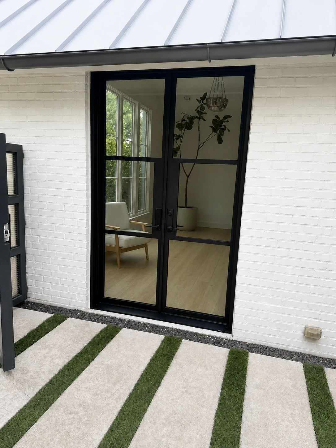 Slim black steel-and-glass lounge double door opening to a calm, light-filled Highland Park interior