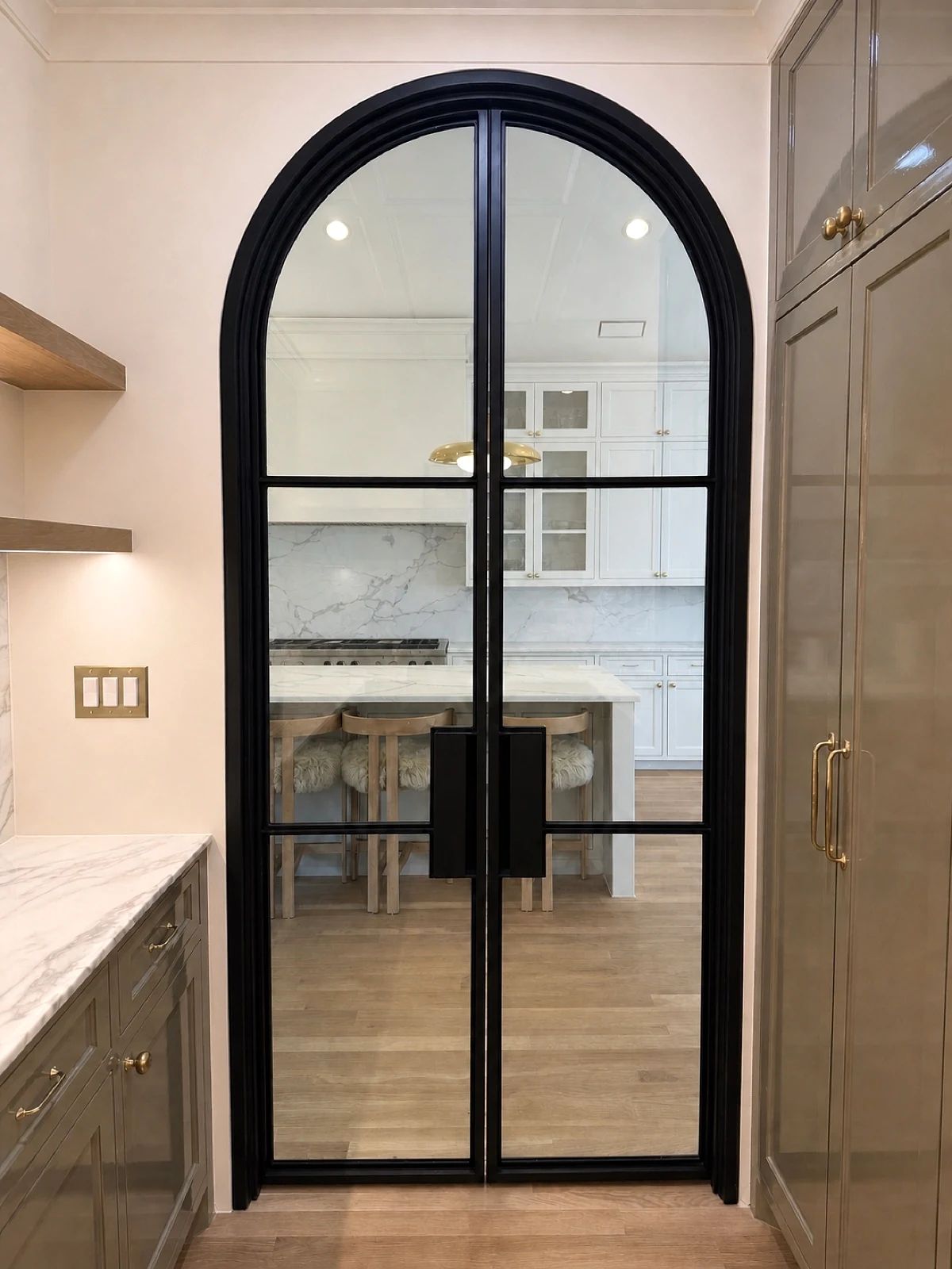 Reverse view through a full-arch steel pantry door toward the kitchen