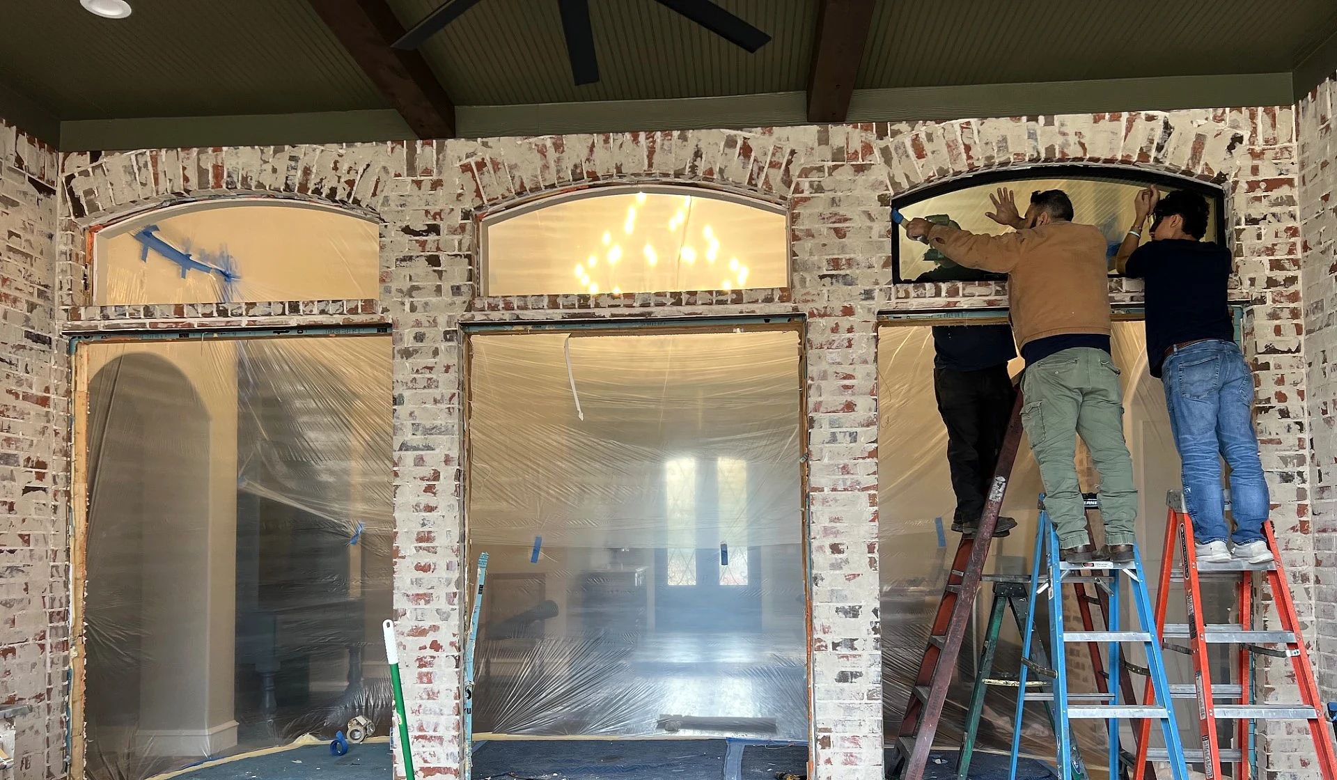 Three D’Hierro installers glazing the right arched transom above the Lucas patio doors