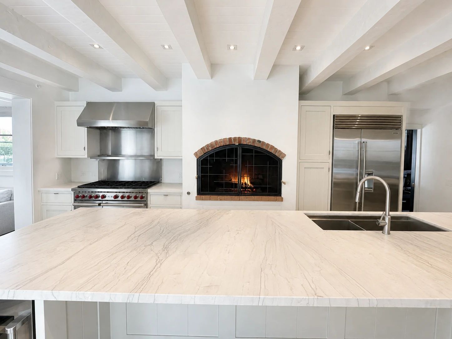 Custom arched charcoal steel fireplace screen centered in a white Montecito kitchen
