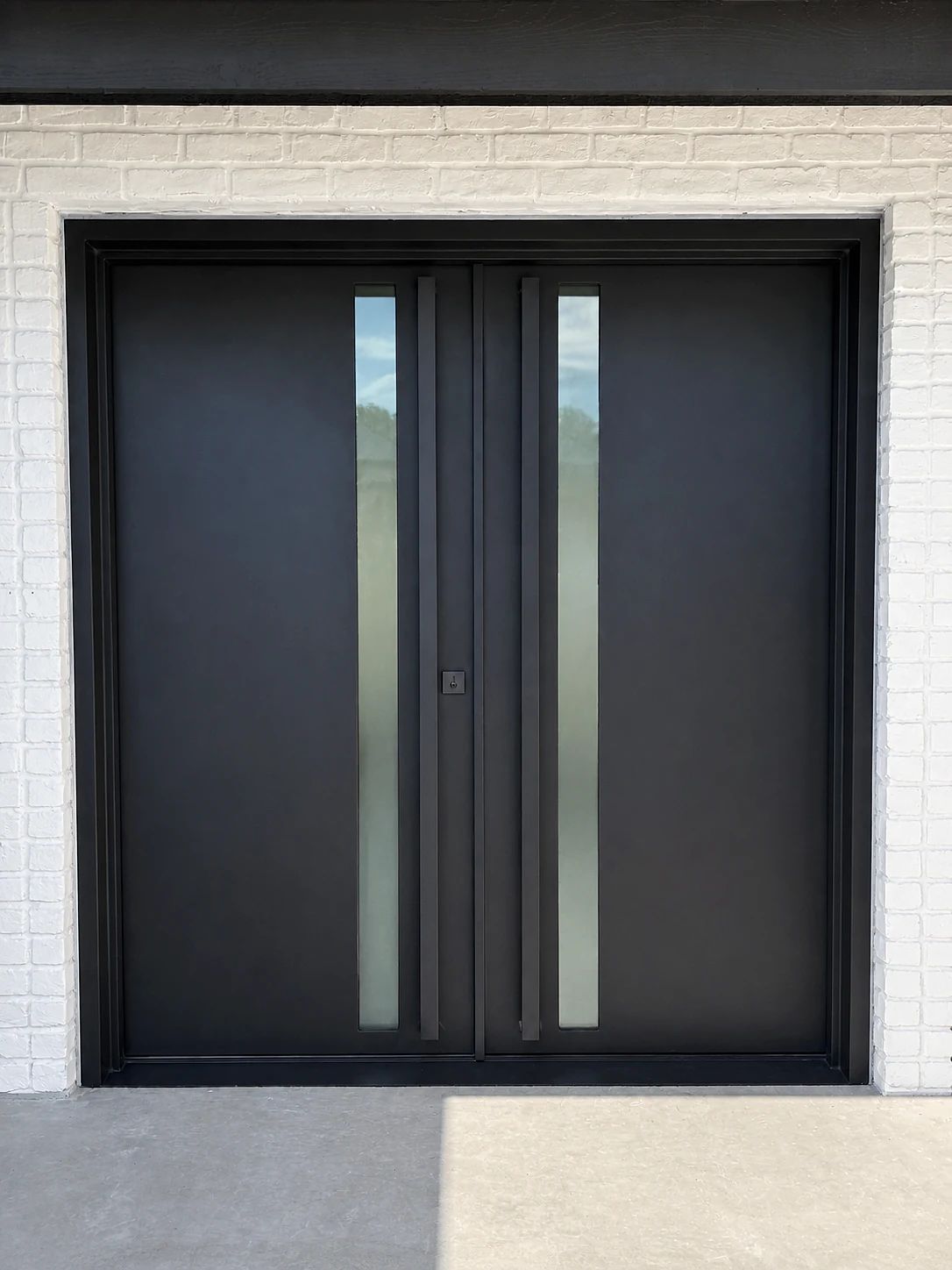 Black steel double entry with narrow satin-glass lites and long pulls at a Plano, Texas residence