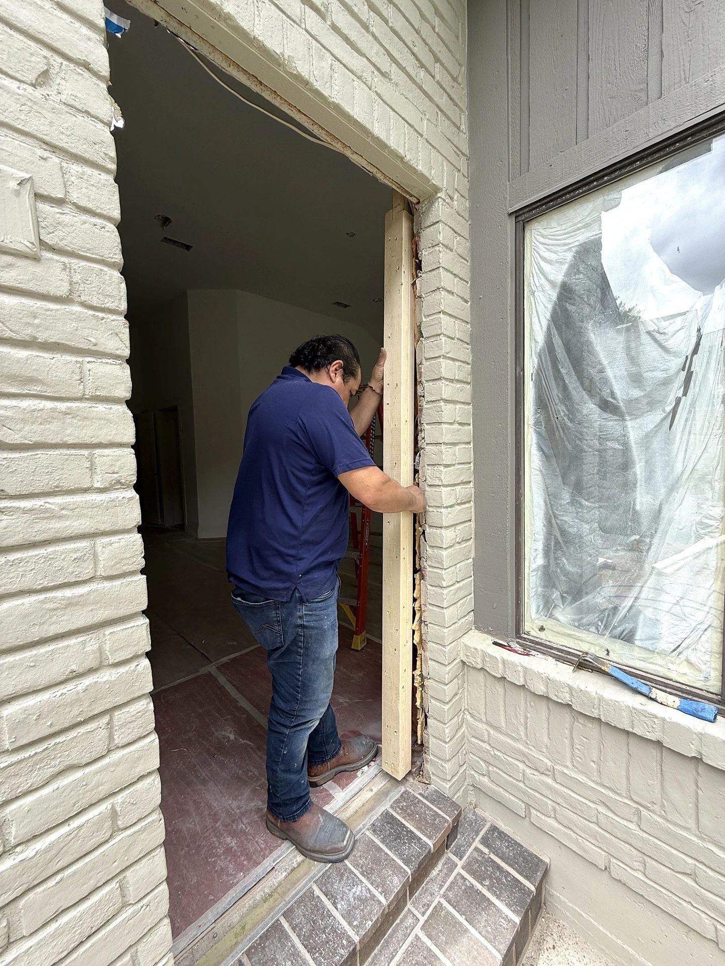 D’Hierro installer fitting the front-entry jamb inside the opened brick surround at a Plano residence