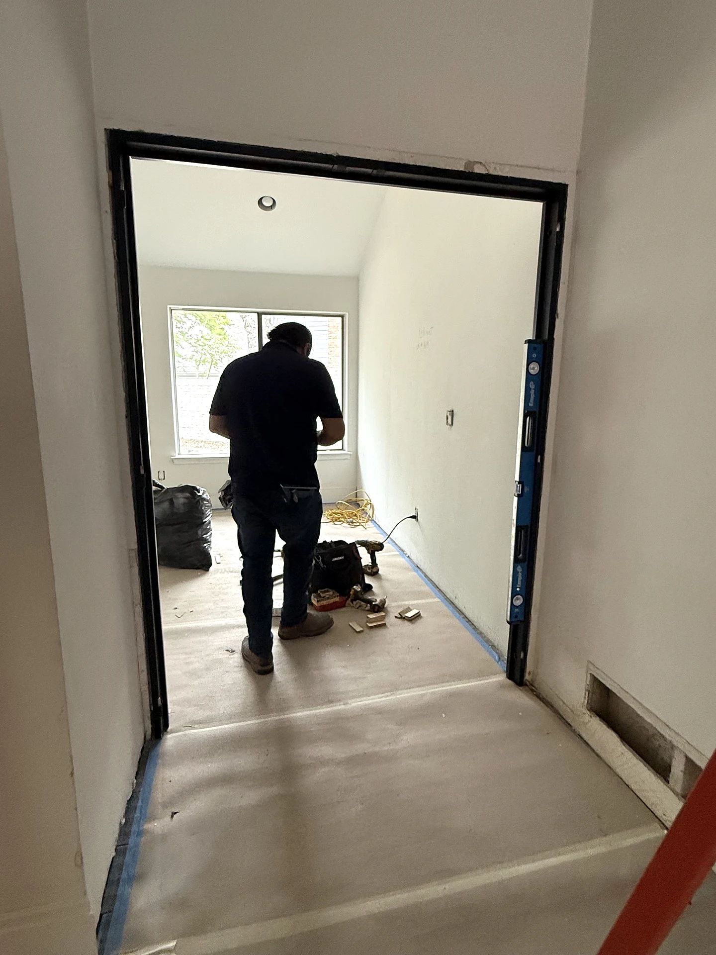 D’Hierro installer setting and leveling the black steel office-door frame in Plano