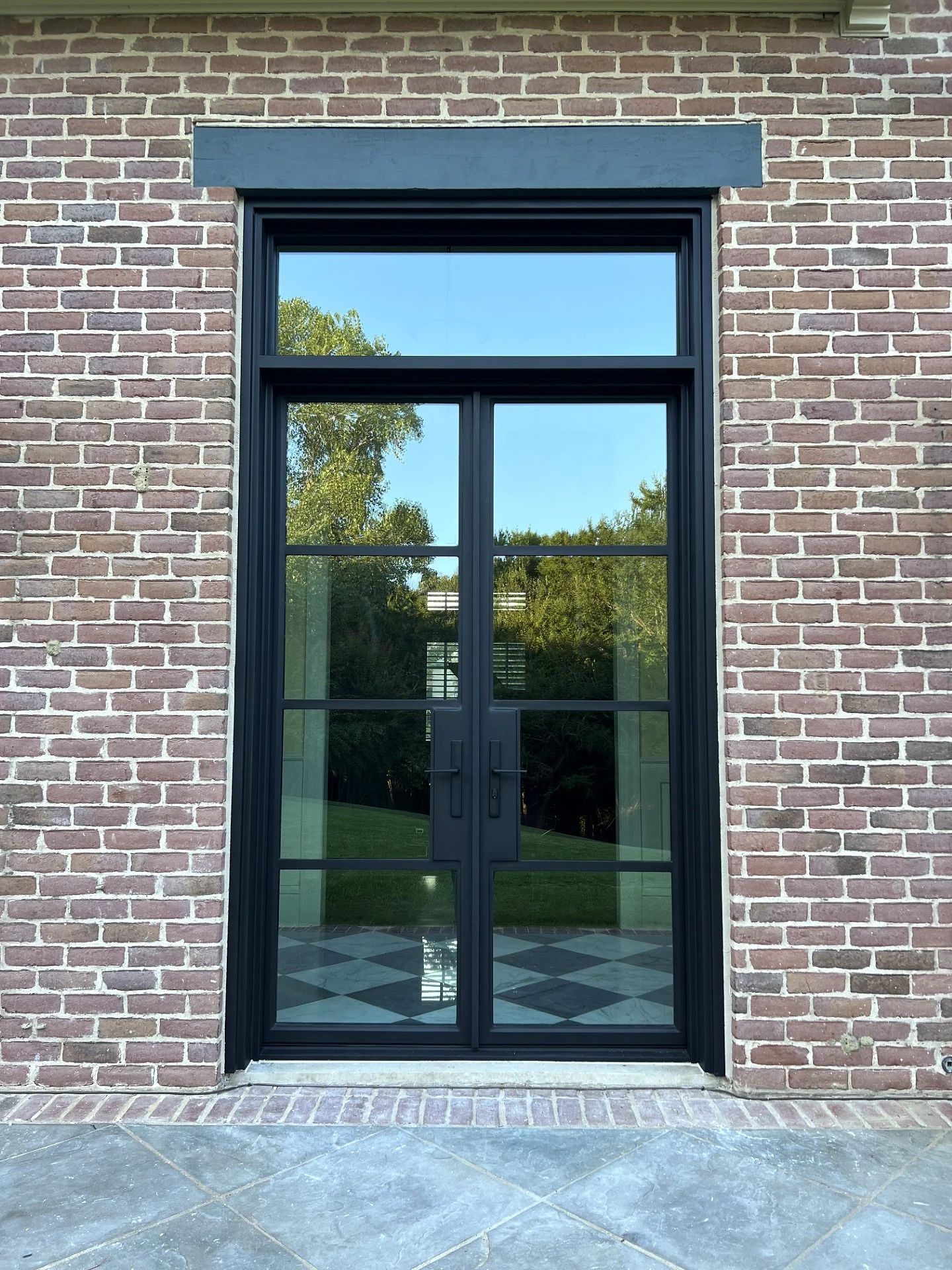 Tall bronze steel-and-glass exterior double door set into a brick wall in Plano