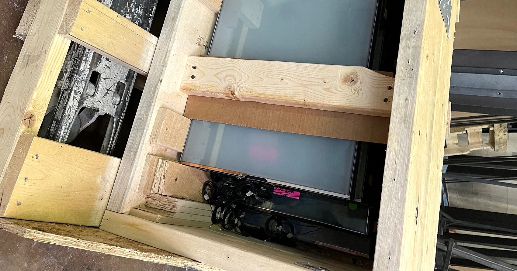 Crated Gauzy switchable insulated-glass units with bundled wire leads before glazing the Plano steel entry