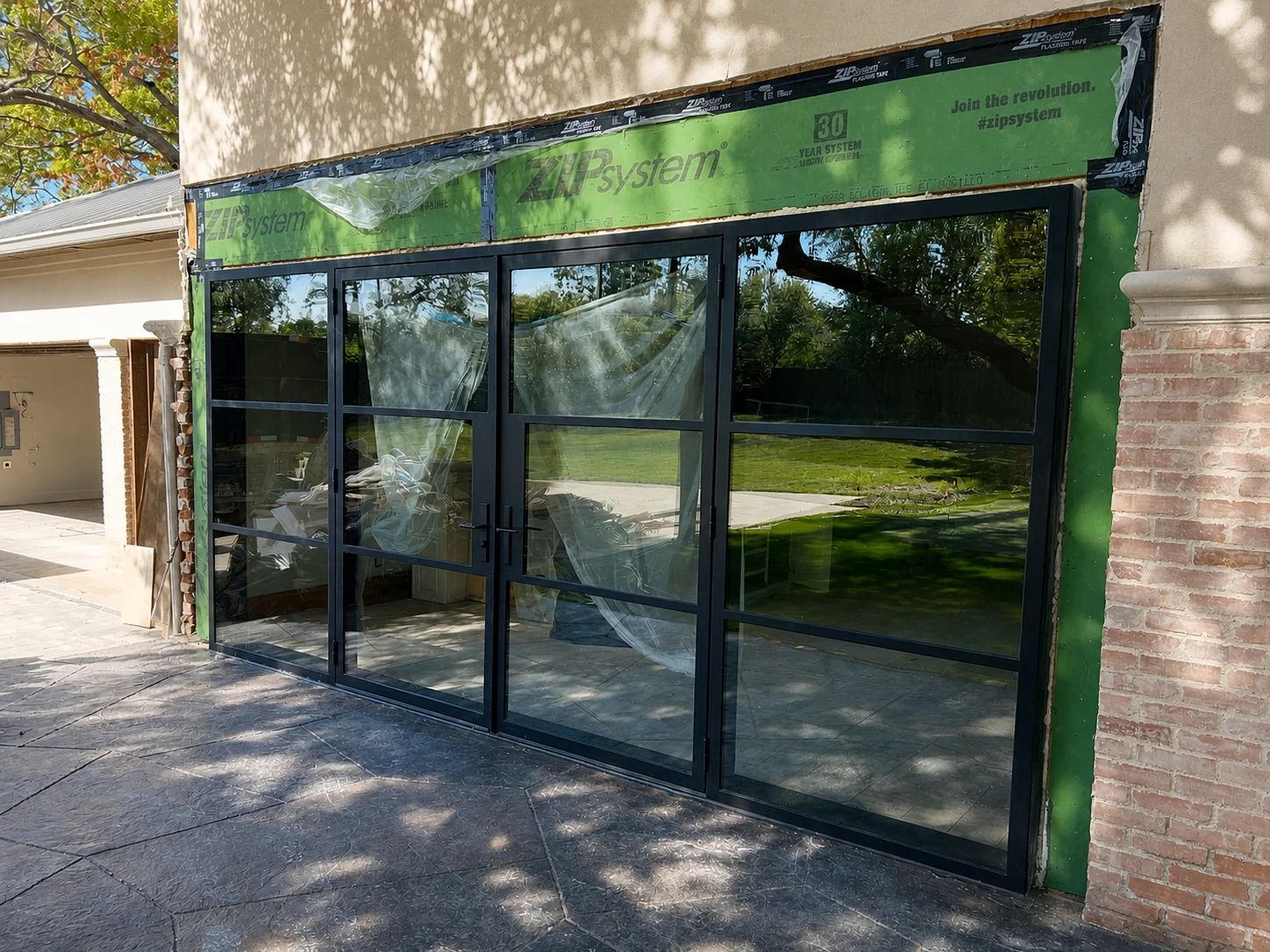 Black steel game-room doors during installation at the rear of a Preston Hollow residence