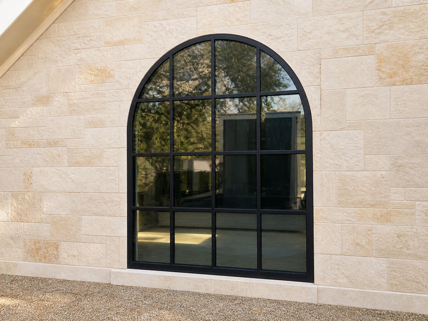 Full-arch black steel window with aligned mullions installed in a limestone opening in Preston Hollow, Dallas