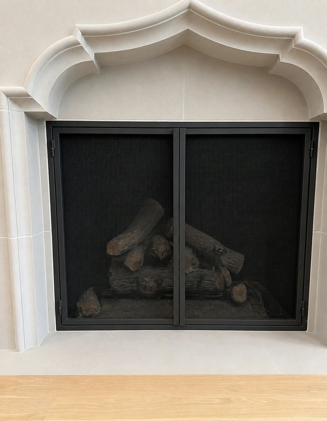 Completed D'Hierro charcoal two-panel fireplace screen within the sculpted pale living-room surround
