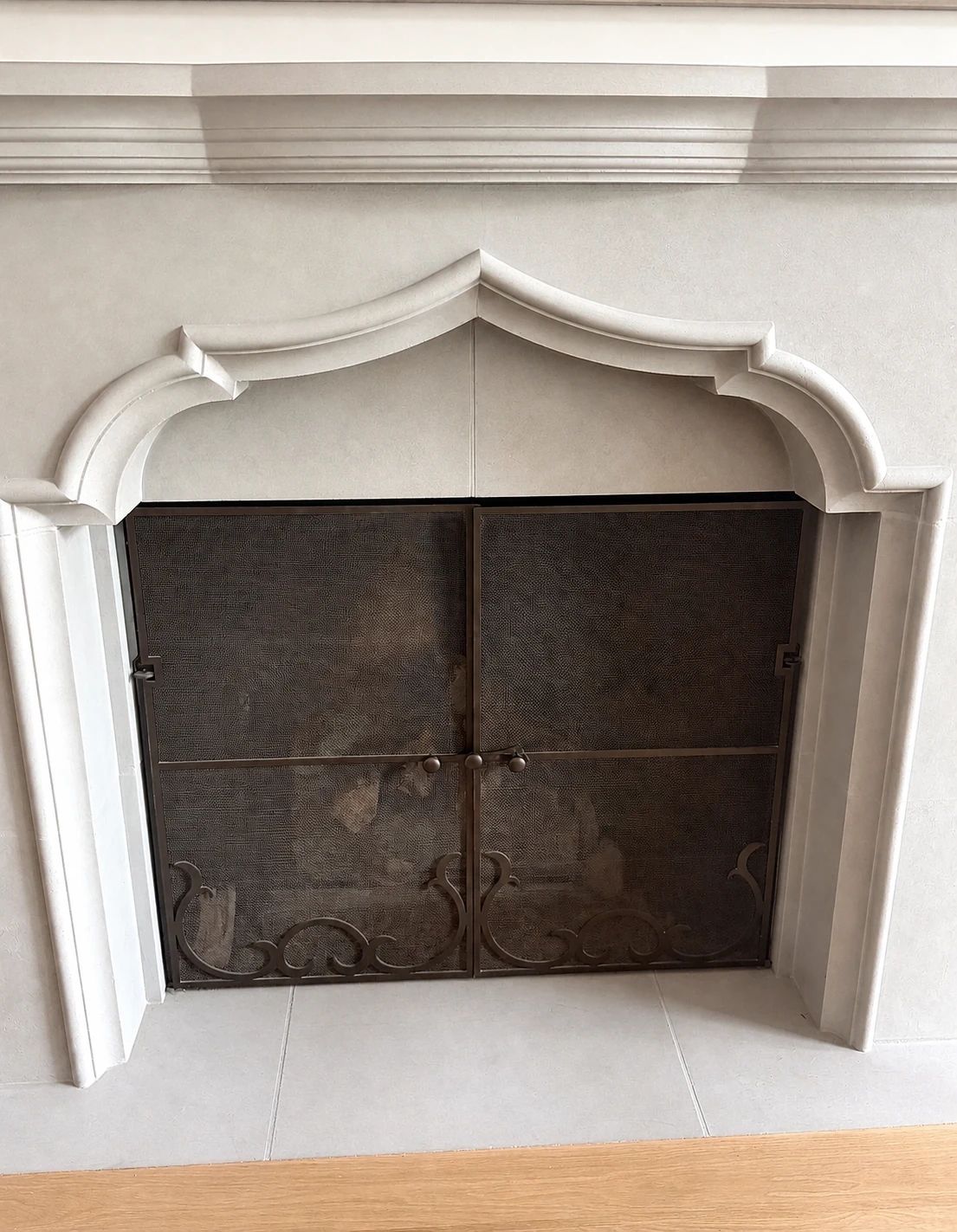 Living-room fireplace opening with the pre-existing ornate screen before D'Hierro's custom charcoal replacement