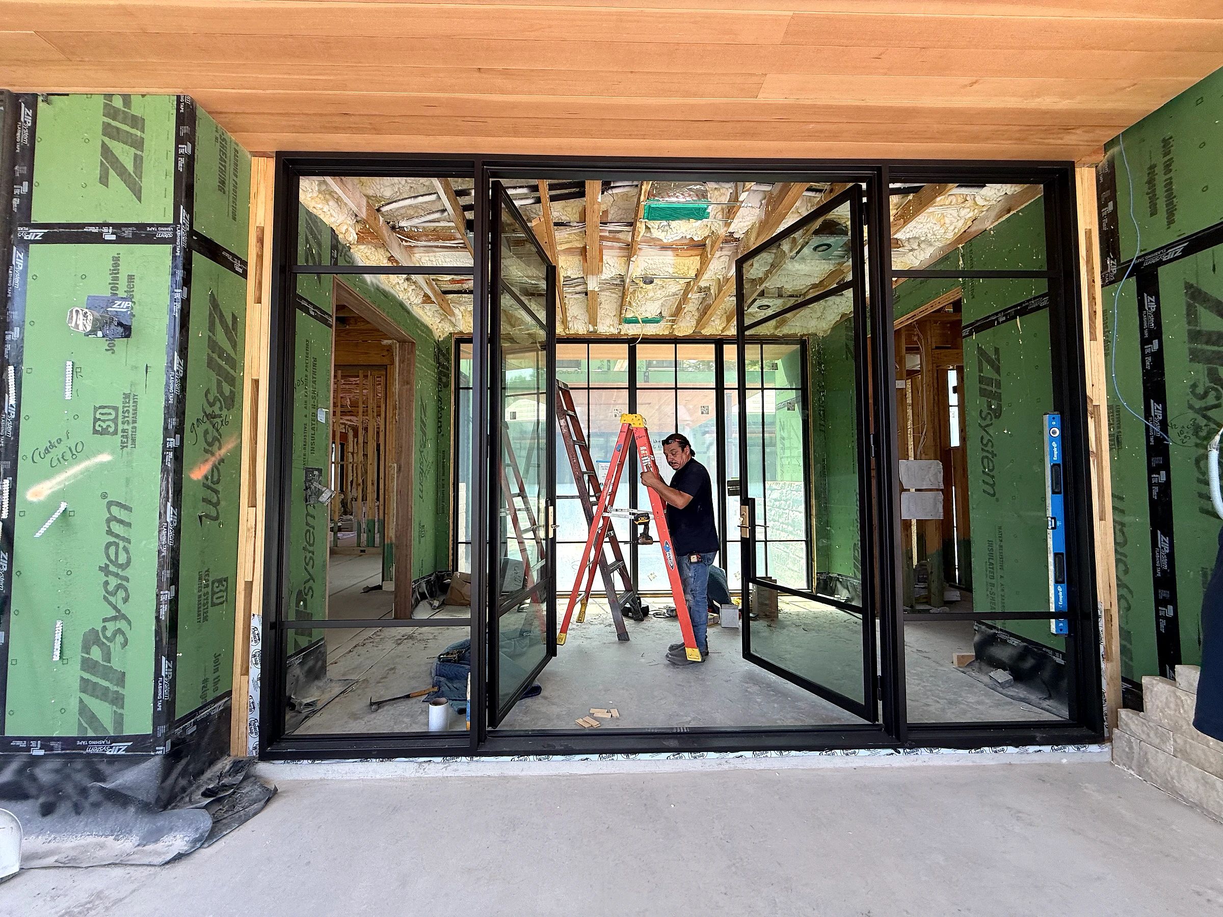 D’Hierro installer checking the complete oversized steel entry frame with both door leaves open in Richardson