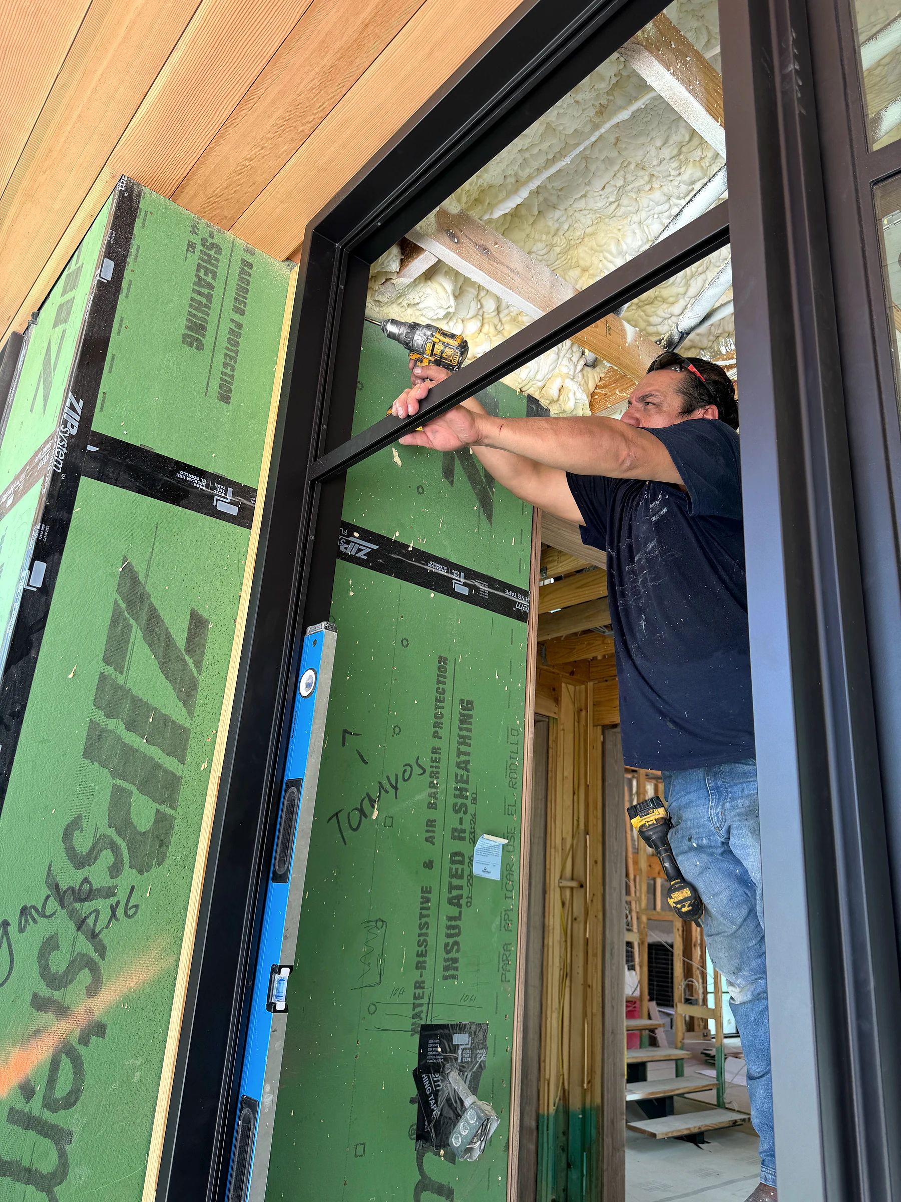 D’Hierro installer fastening and leveling the bronze steel entry frame at the unfinished jamb