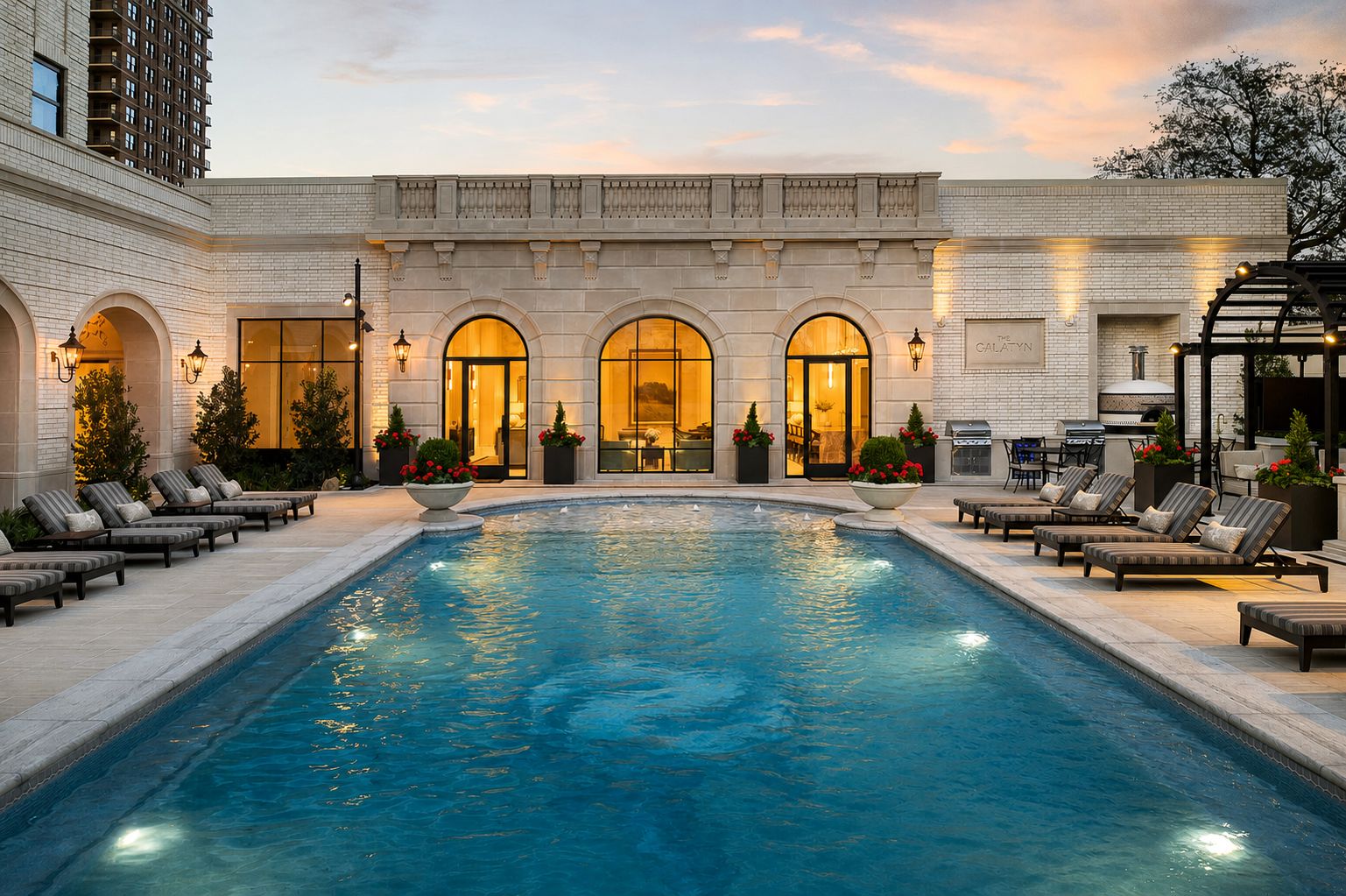 Pool courtyard with sheer-descent fountain wall and loggia at dusk