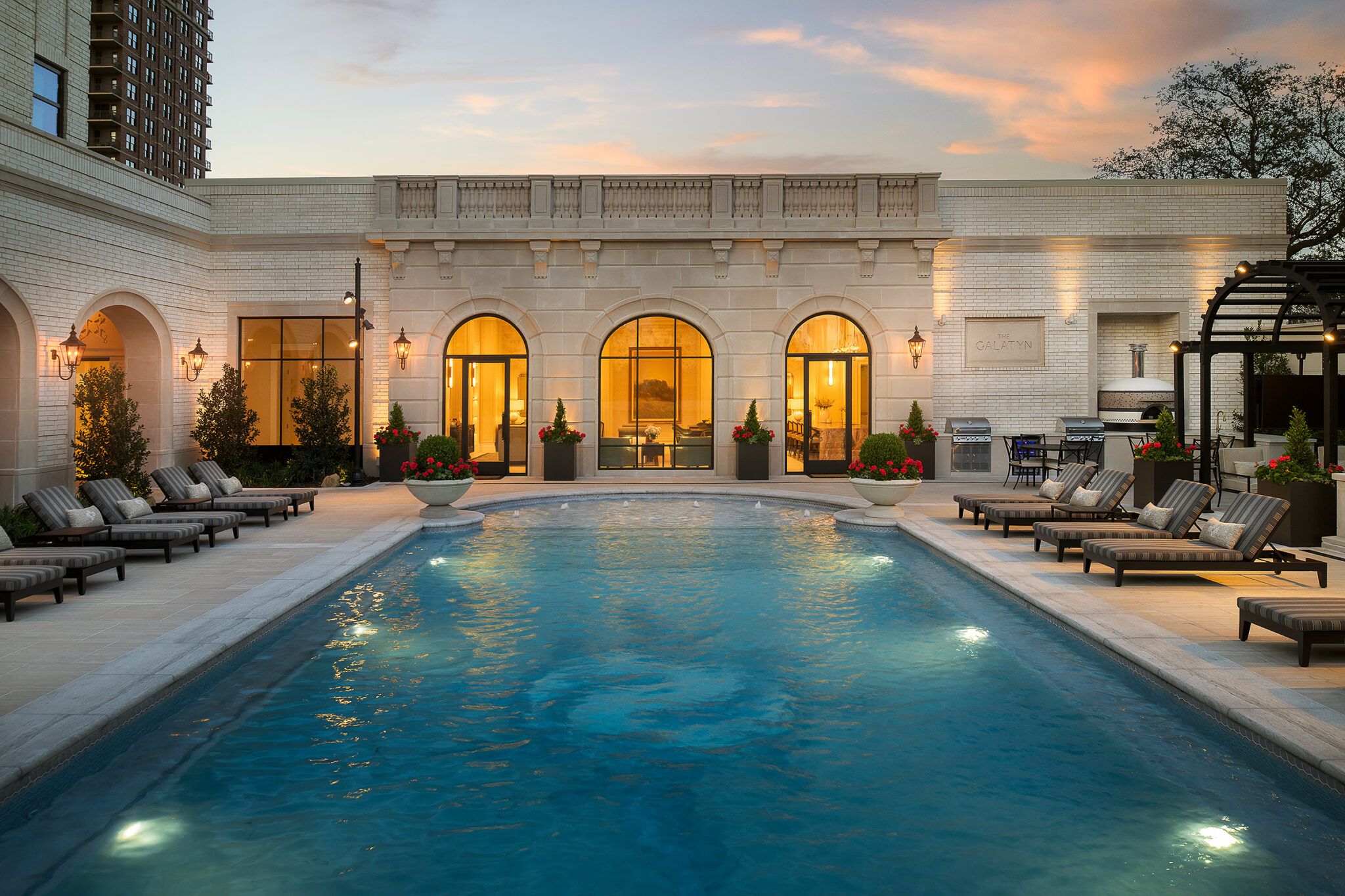 Pool courtyard with sheer-descent fountain wall and loggia at dusk