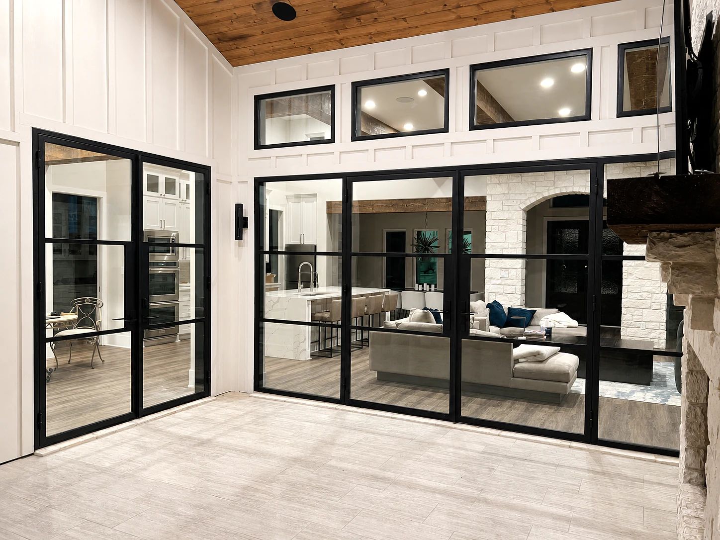 Wide black steel double-door assembly with sidelites and four transom windows at a Trinidad, Texas lakehouse