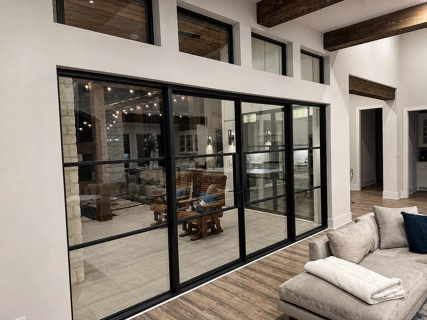 Interior view through the completed black steel lakehouse door wall toward the covered patio and lake