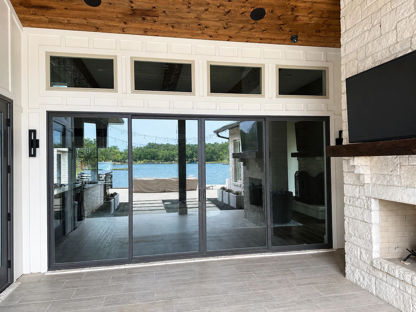 Trinidad lakehouse back wall before installation with gray aluminum sliding doors and white transom windows