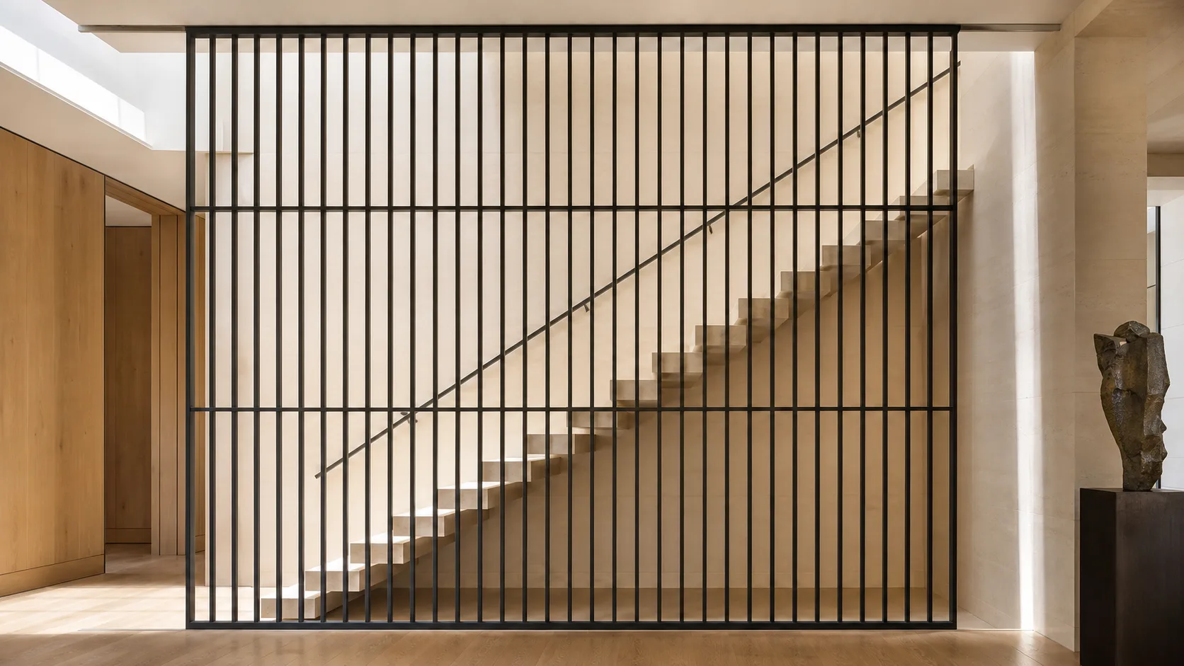 Double-height limestone stair behind an evenly spaced steel railing screen